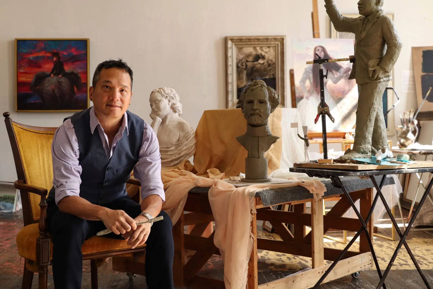 Andrew Luy seated in his Lowe Mill studio among sculptures